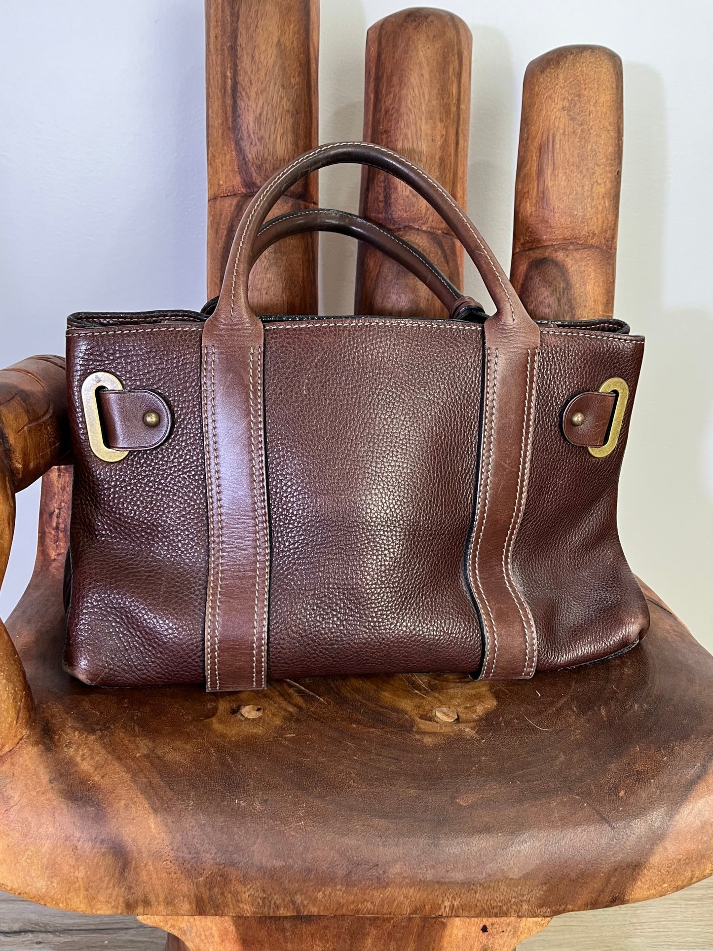 back of Close-up of vintage Luella Stevie Tote in brown leather showing padlock closure, heart charms, and grommet strap with one missing eyelet.