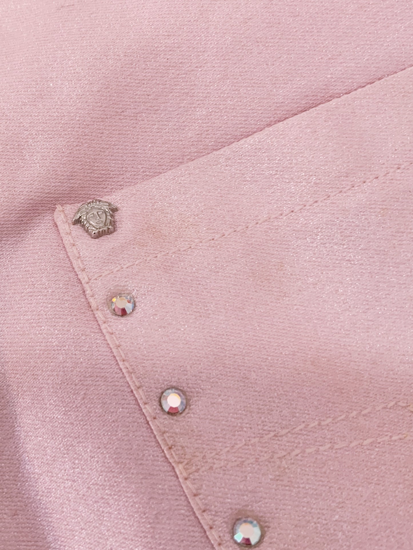 Close-up of a pink fabric with Medusa hard wear and rhinestones