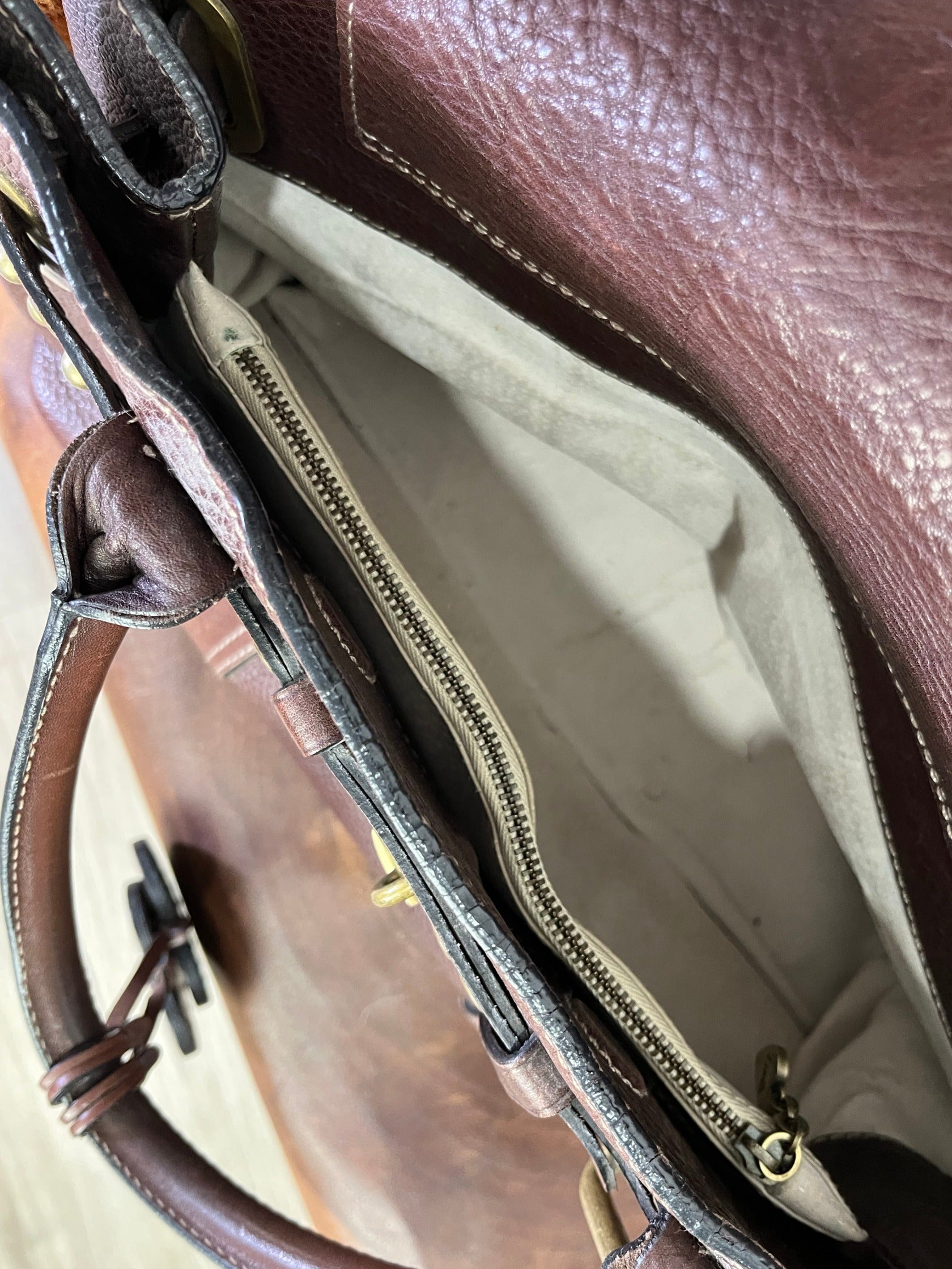 inside of  vintage Luella Stevie Tote in brown leather showing padlock closure, heart charms, and grommet strap with one missing eyelet.