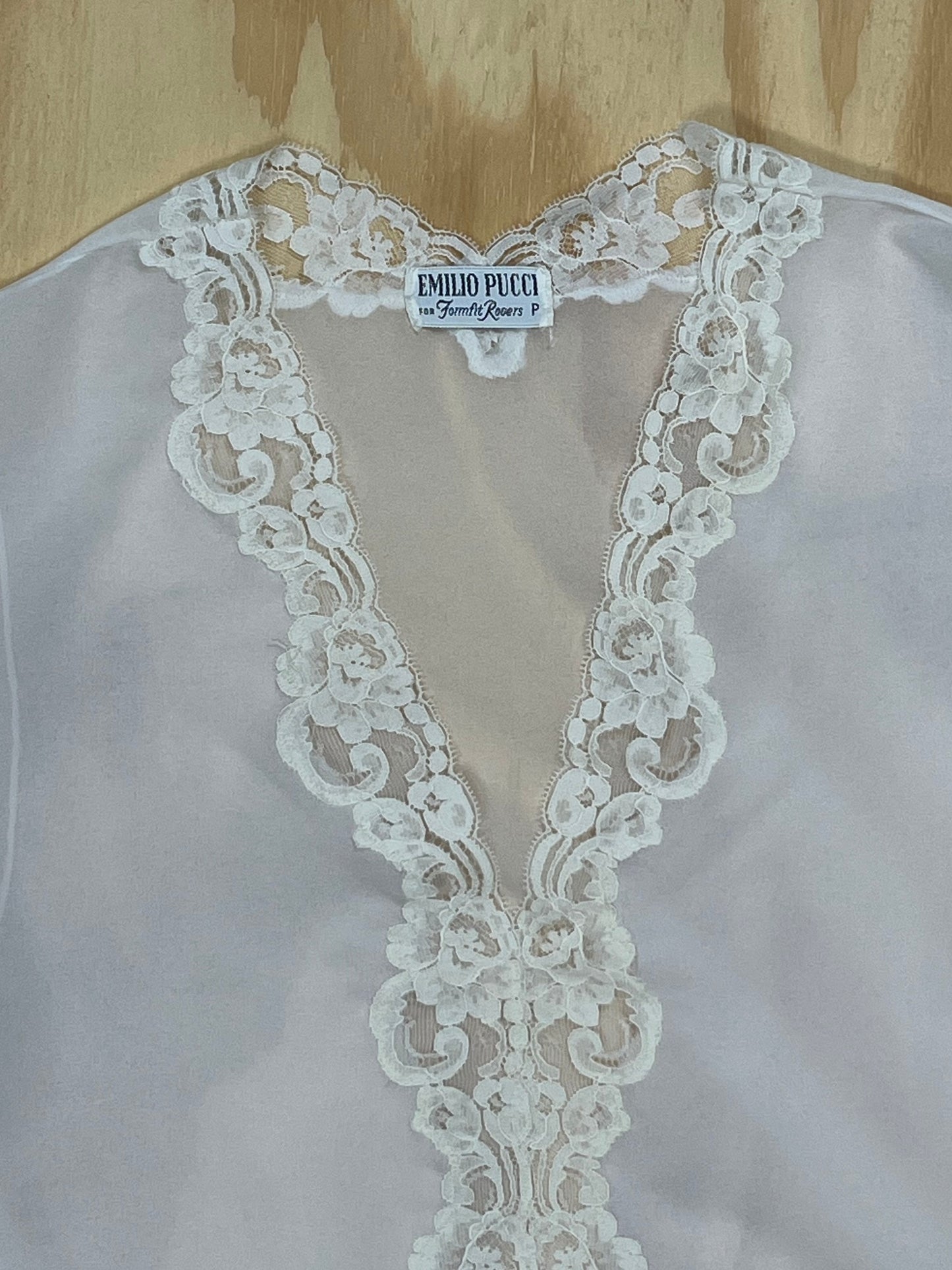 Close-up of Emilio Pucci for Fornell Rogers label on white lace blouse.