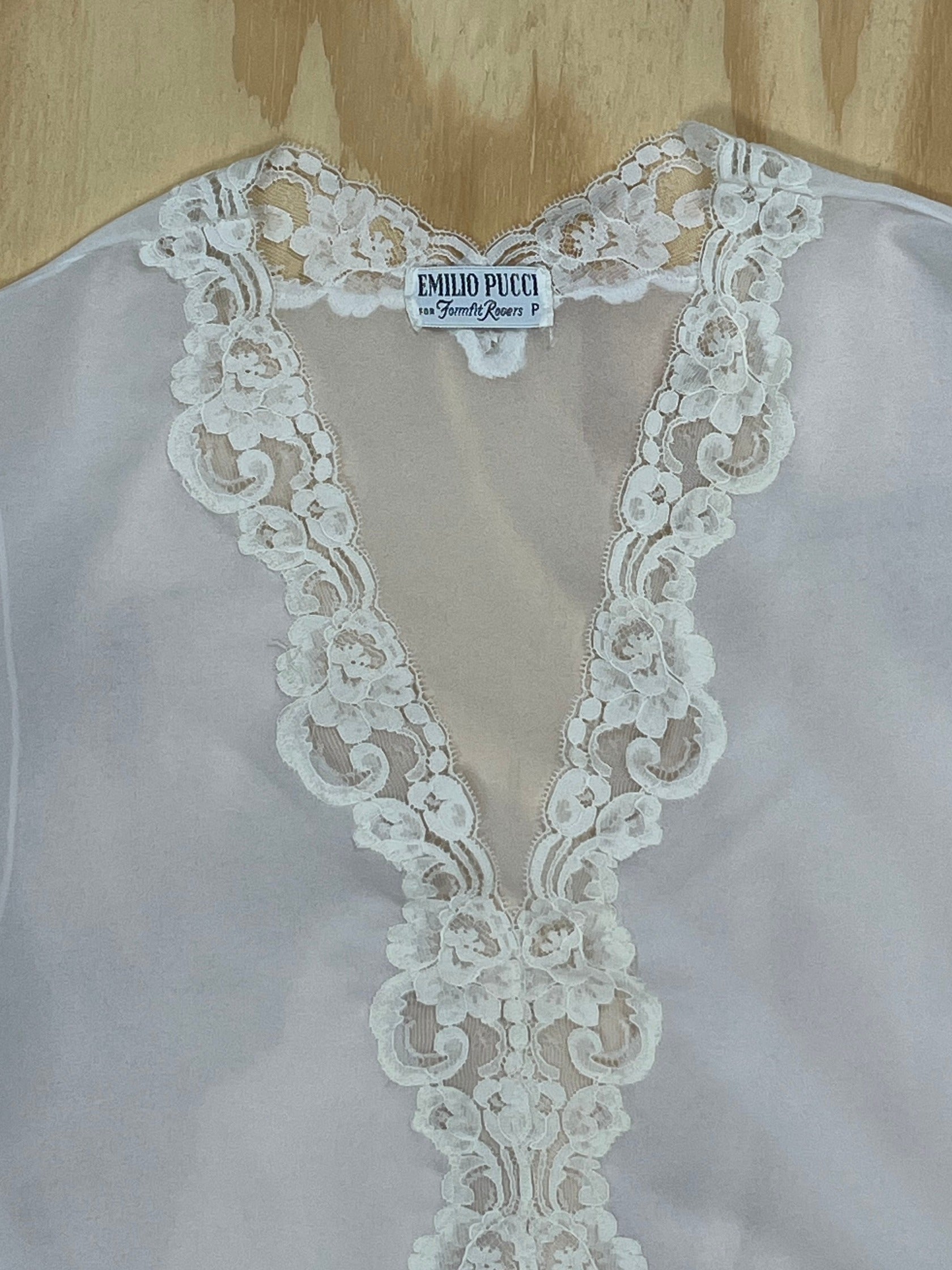 Close-up of Emilio Pucci for Fornell Rogers label on white lace blouse.