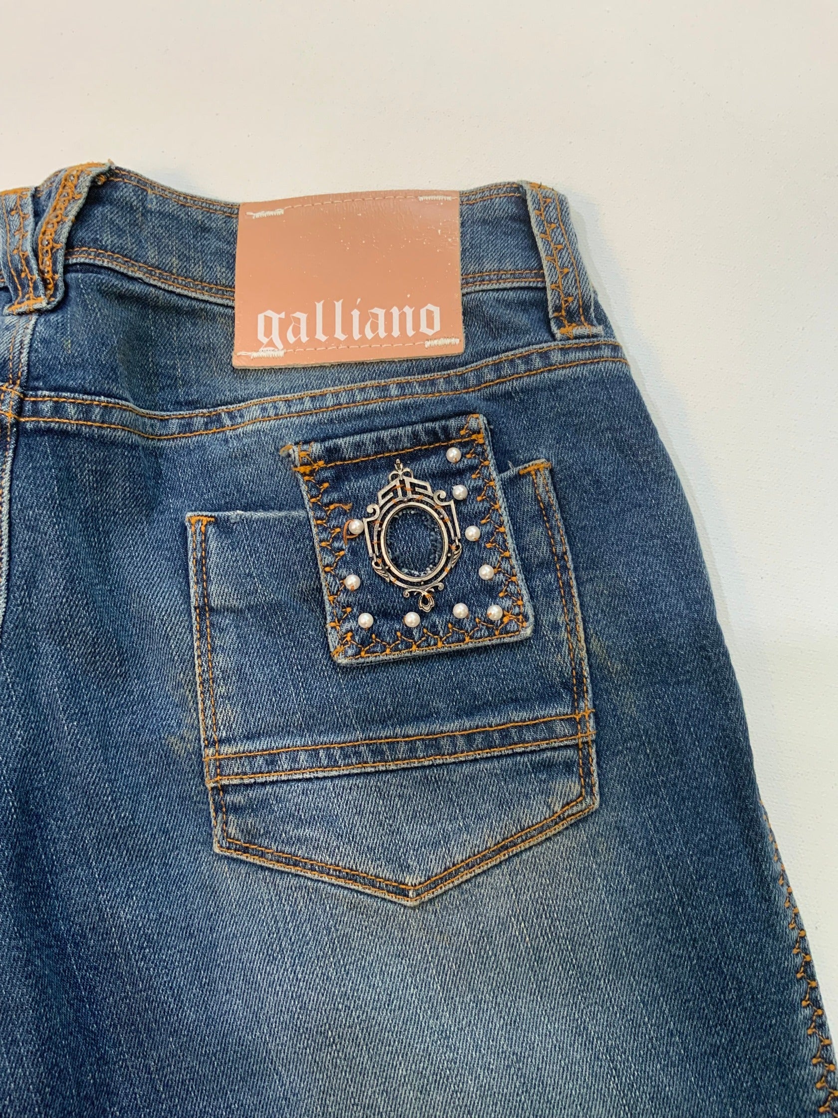 back of Vintage Galliano mid-wash denim jeans with pearl studded front pockets, embellished back pocket patch with pearls and silver detail, and cropped hem.