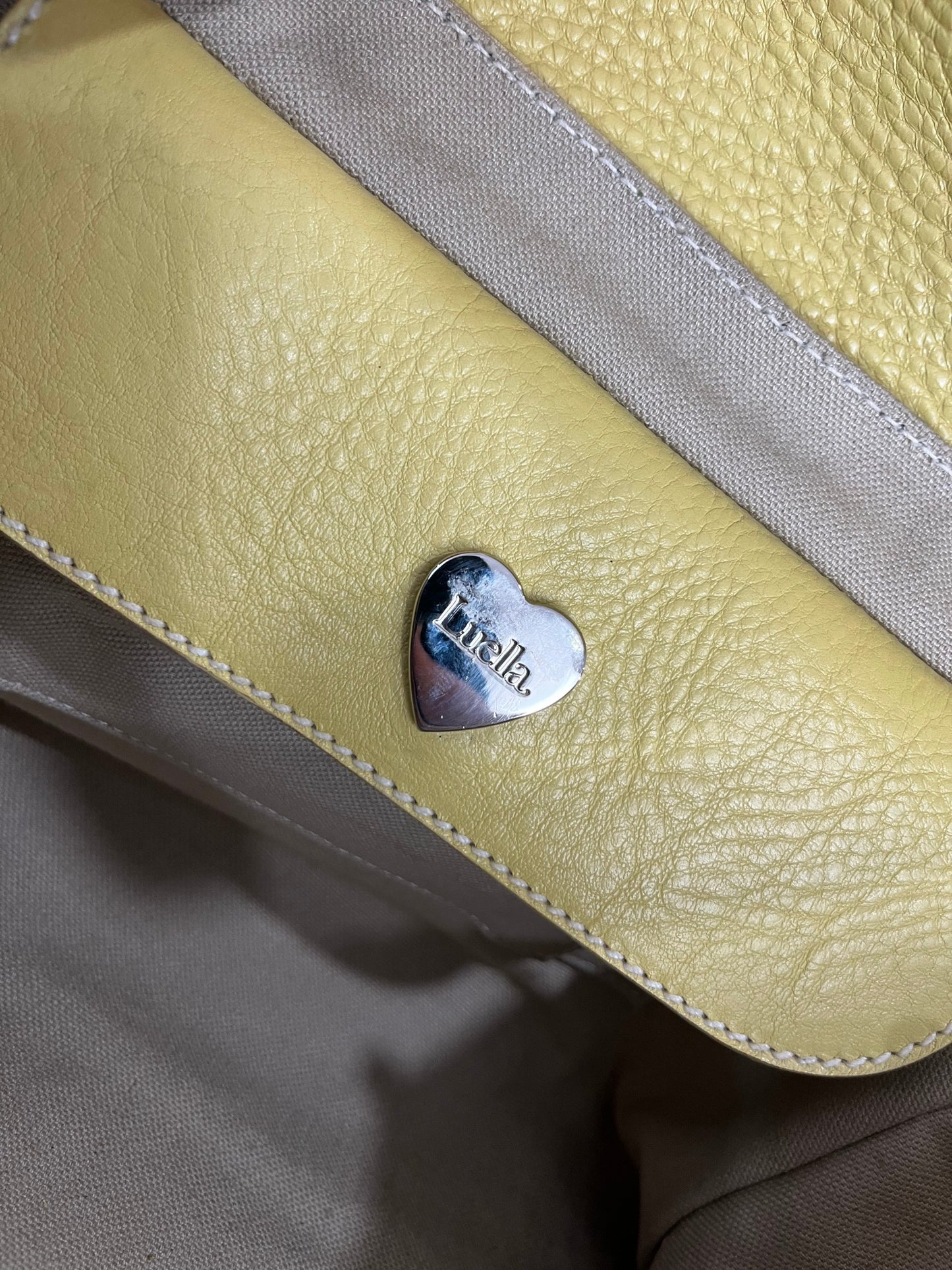 inside of Vintage Luella Gisele bag in yellow grained leather with silver hardware, buckle details, and signature heart charm, iconic early 2000s It-bag.