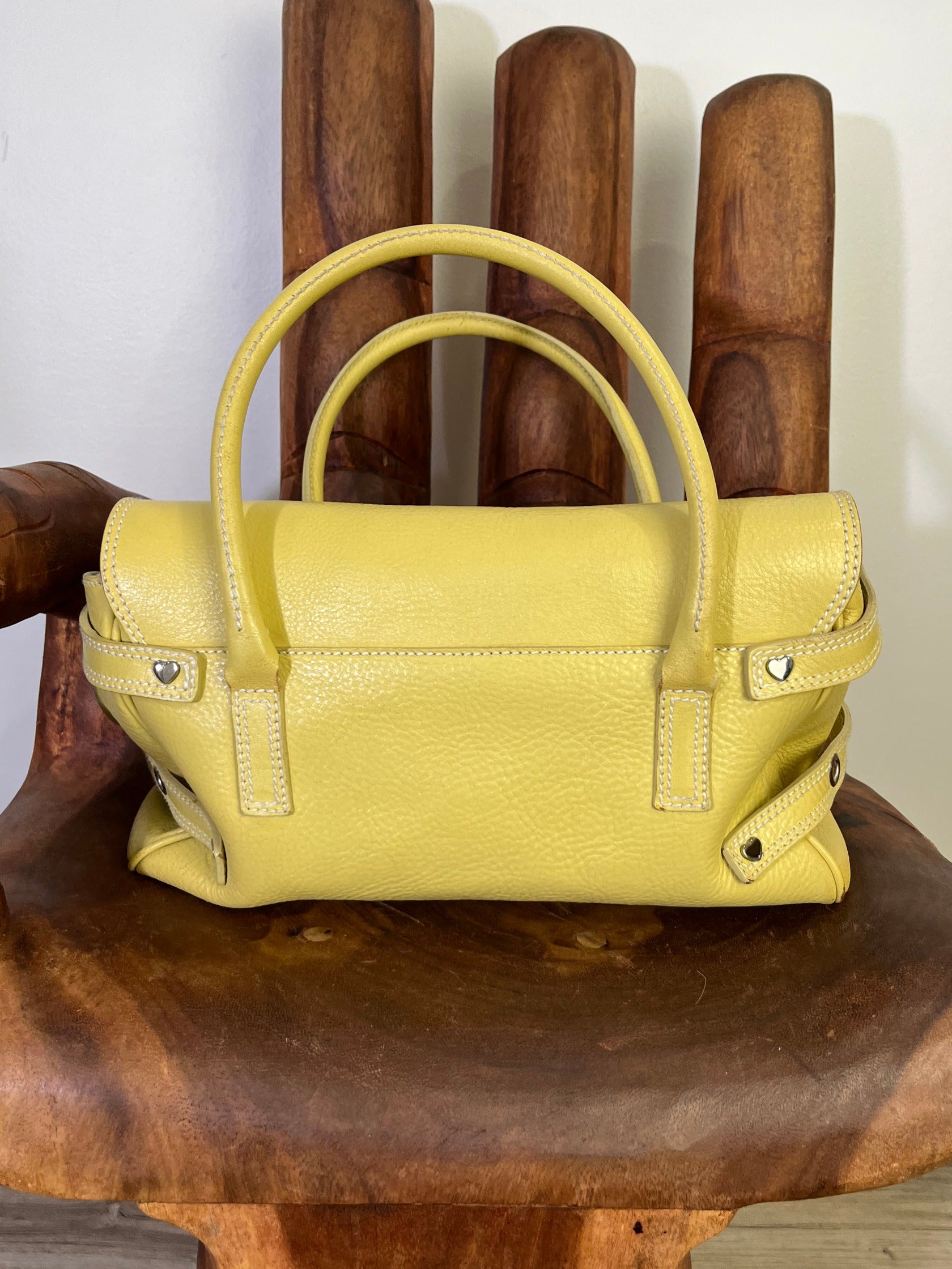 back of Vintage Luella Gisele bag in yellow grained leather with silver hardware, buckle details, and signature heart charm, iconic early 2000s It-bag.