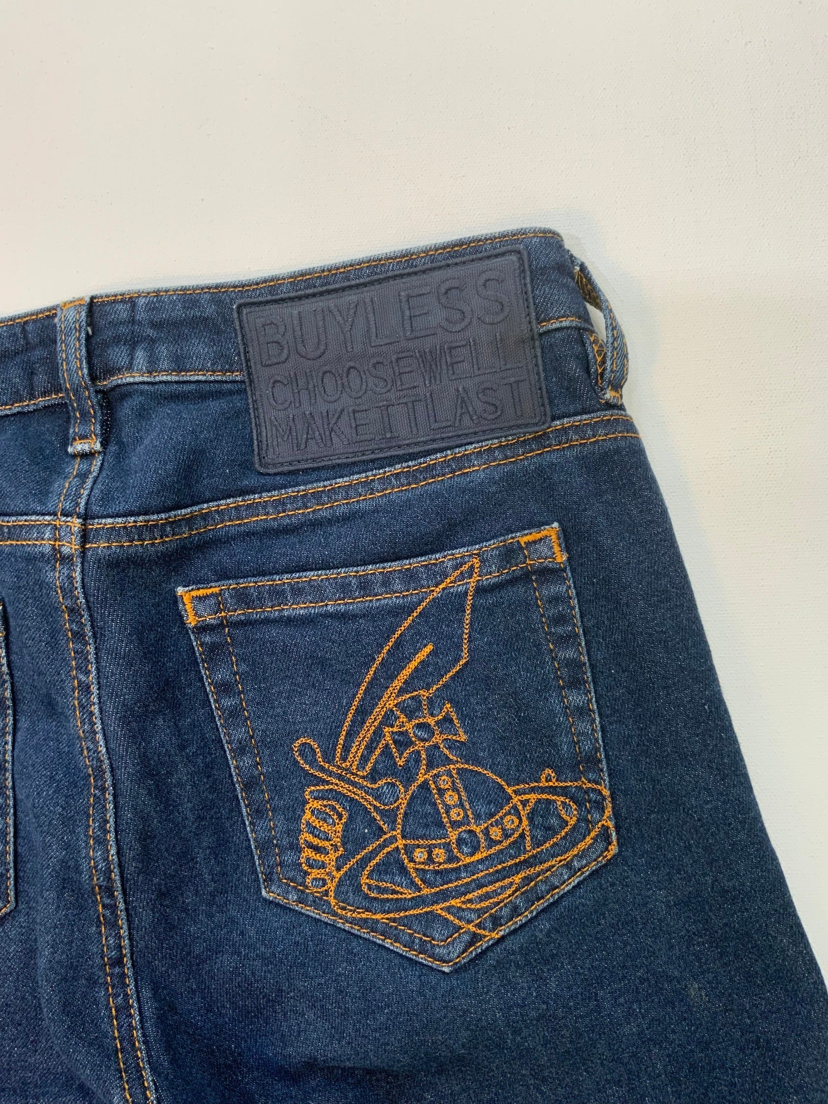 back pocket Vivienne Westwood dark blue skinny jeans with gold Orb embroidery on back pocket and black “Buy Less, Choose Well, Make It Last” patch at waistband. 