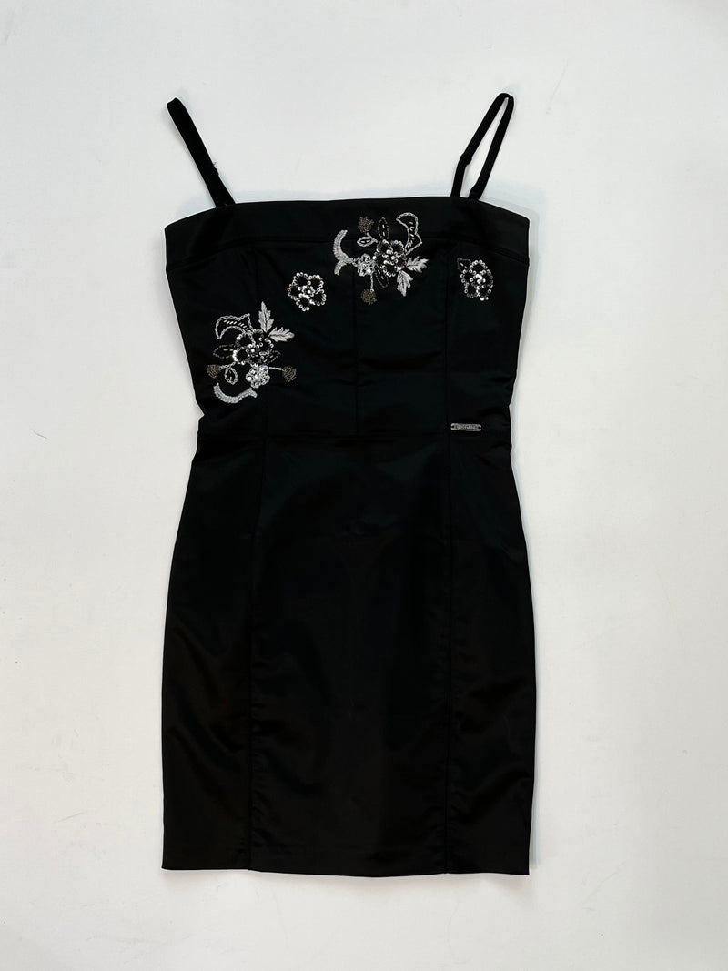 Galliano black satin mini dress with silver and white floral embroidery, fitted silhouette, adjustable straps, and logo plaque at waist.