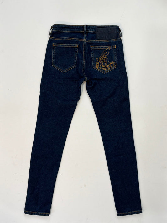 back of Vivienne Westwood dark blue skinny jeans with gold Orb embroidery on back pocket and black “Buy Less, Choose Well, Make It Last” patch at waistband.