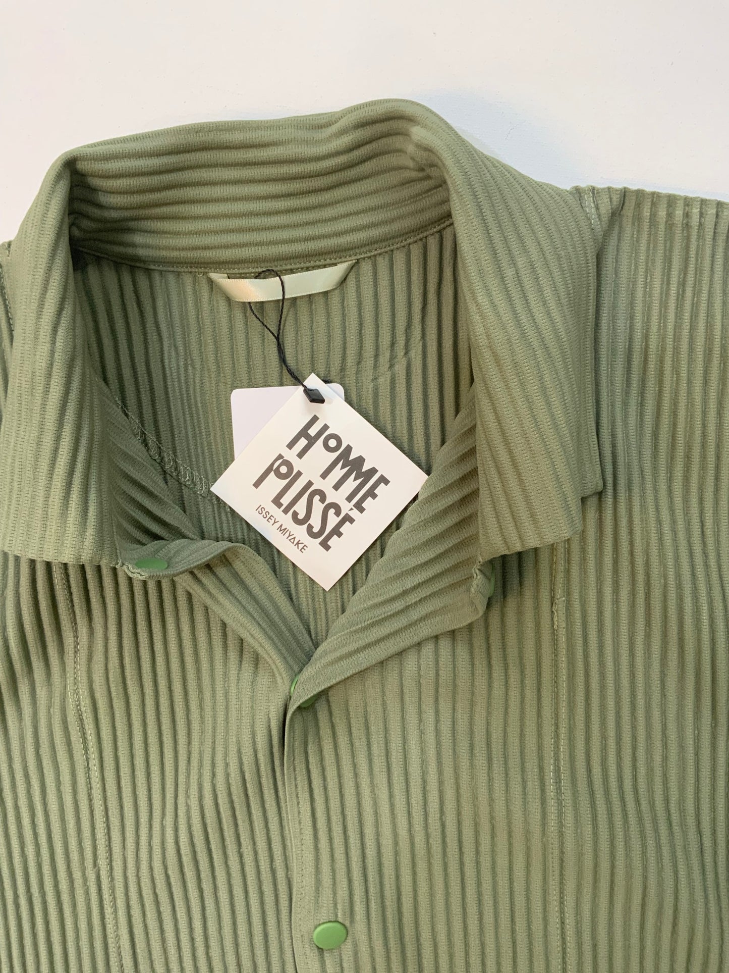 Issey Miyake Homme Plissé black pleated hoodie with drawstring hood, snap-button neckline, and kangaroo pocket.