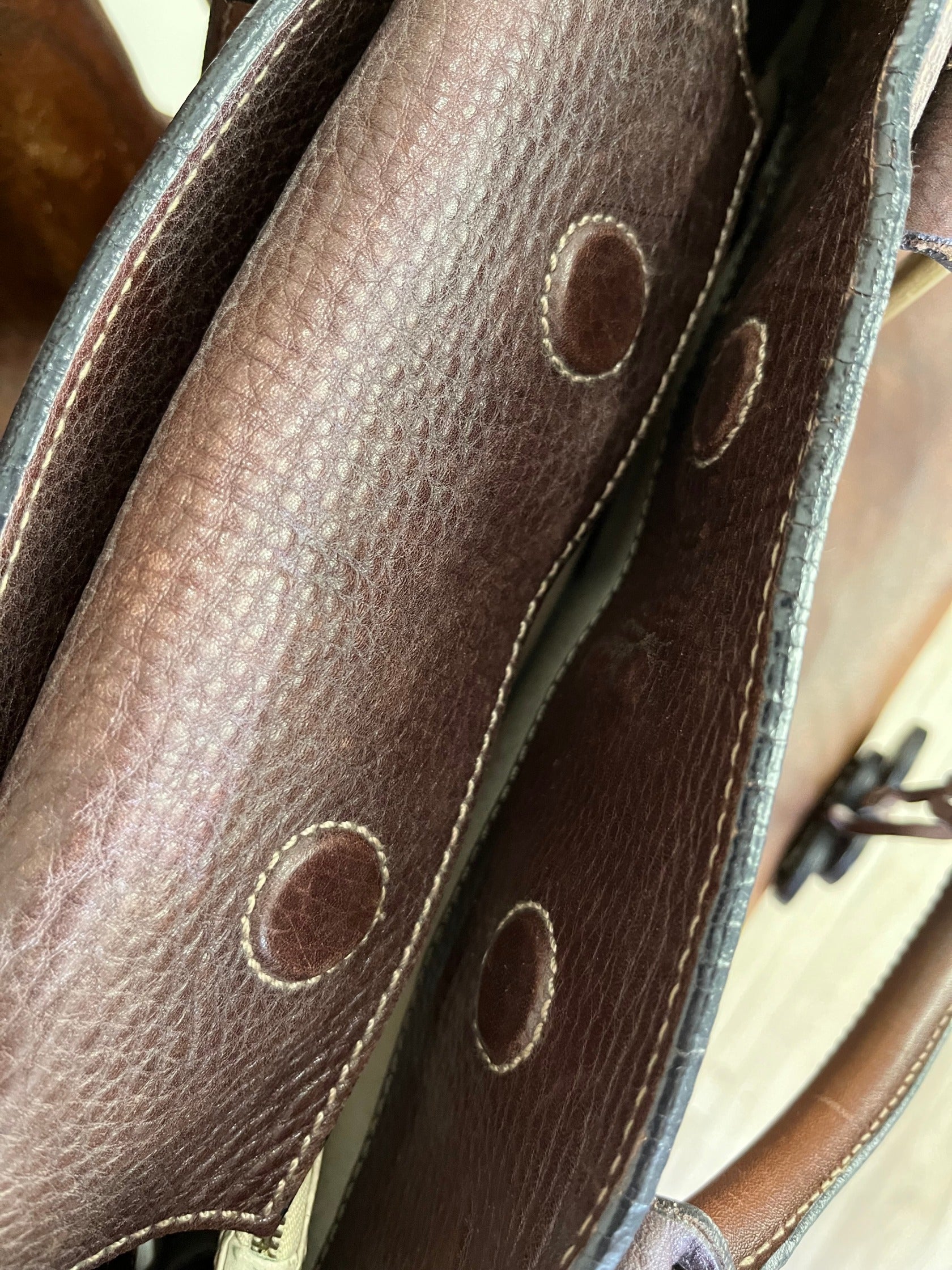 inside - magnetic closure of Close-up of vintage Luella Stevie Tote in brown leather showing padlock closure, heart charms, and grommet strap with one missing eyelet.