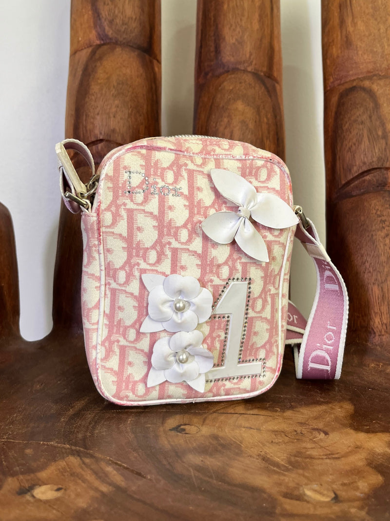Front view of vintage Dior pink logo crossbody bag with floral appliqué, rhinestones, and number 1 detail.