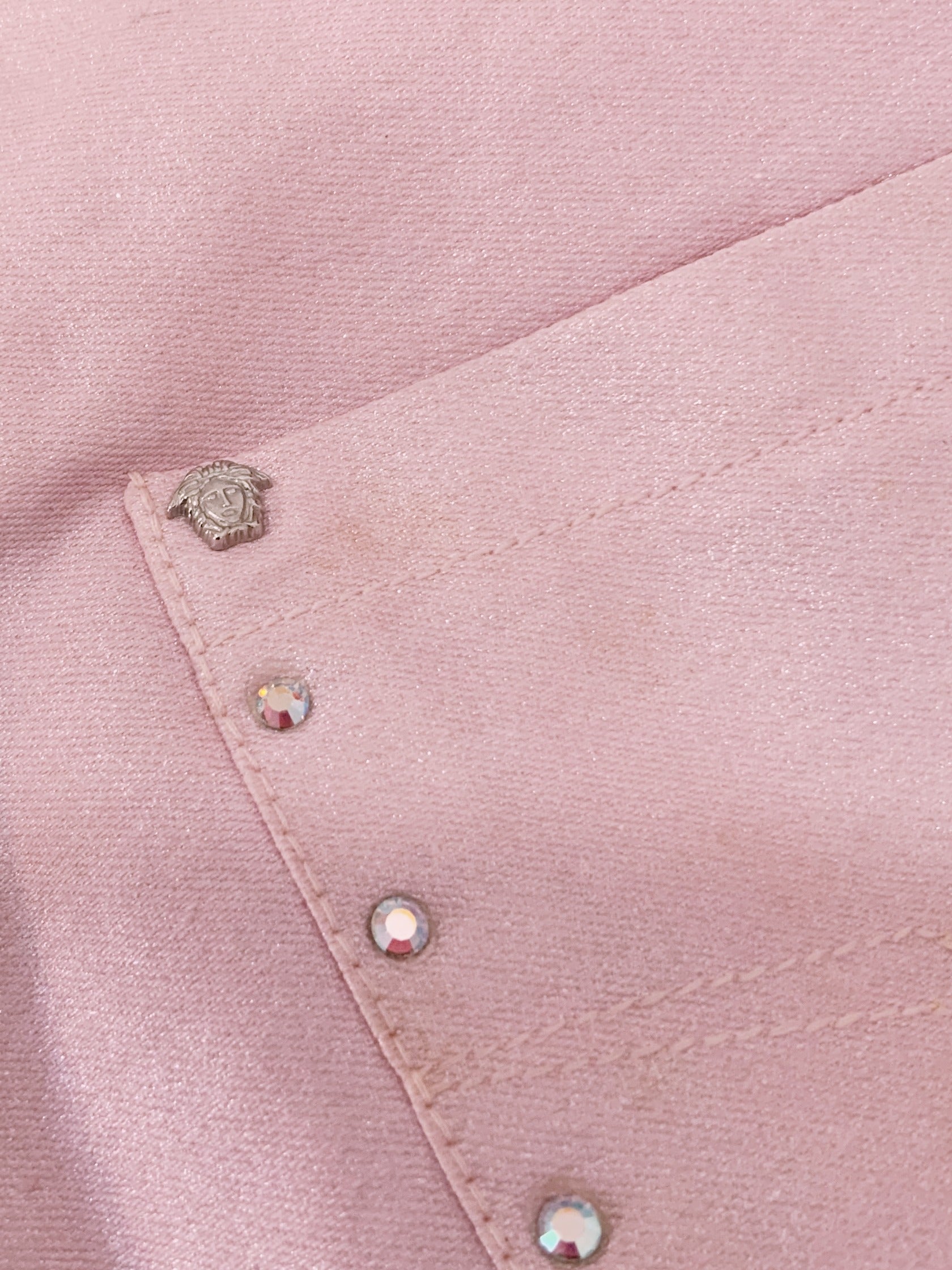 Close-up of a pink fabric with Medusa hard wear and rhinestones 