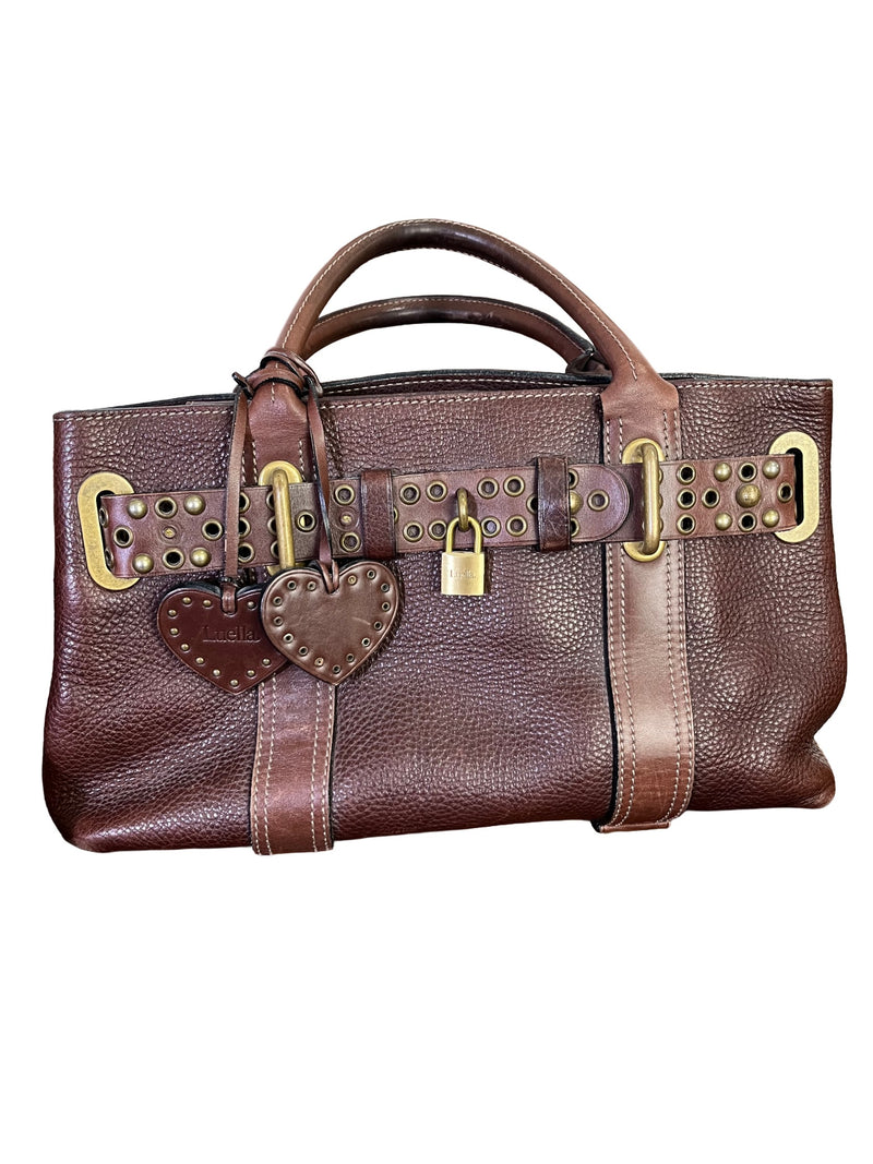 Close-up of vintage Luella Stevie Tote in brown leather showing padlock closure, heart charms, and grommet strap with one missing eyelet.