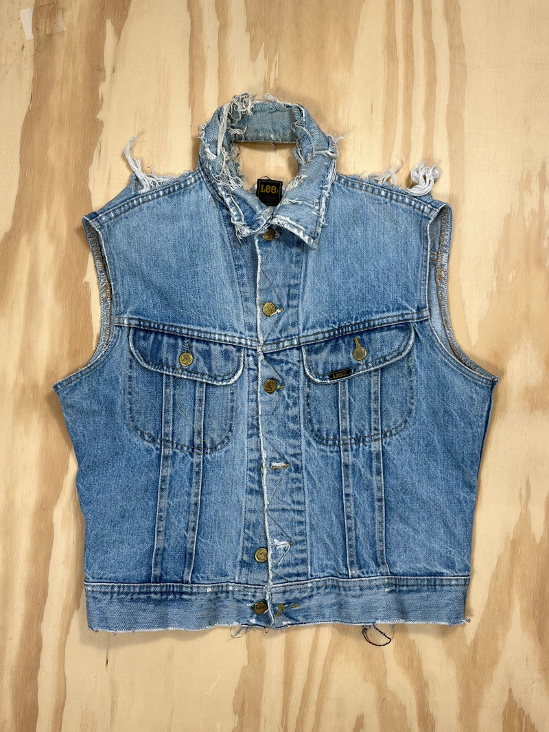 Front view of vintage Lee distressed denim vest with frayed shoulders and brass buttons.