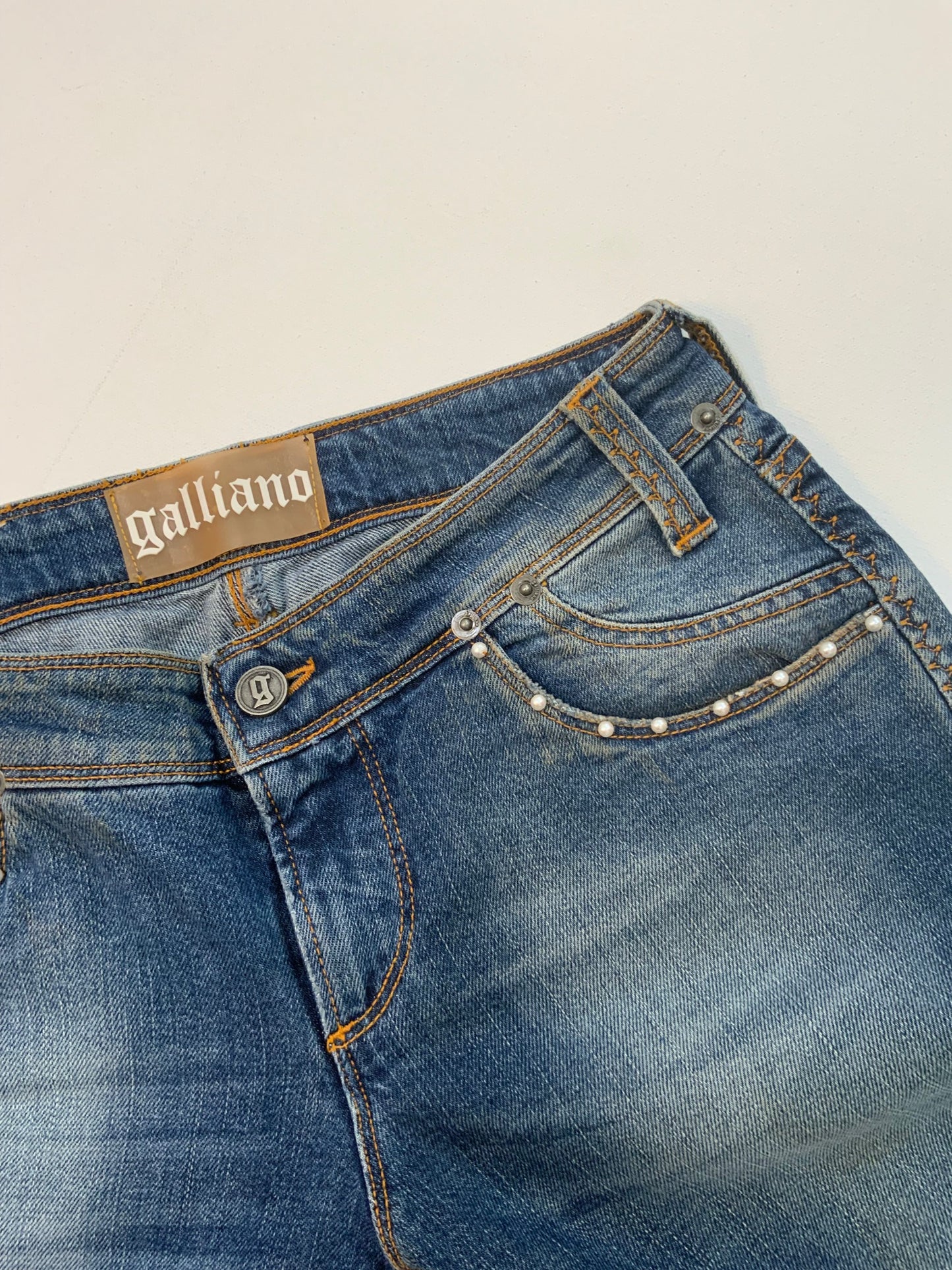 Vintage Galliano mid-wash denim jeans with pearl studded front pockets, embellished back pocket patch with pearls and silver detail, and cropped hem.